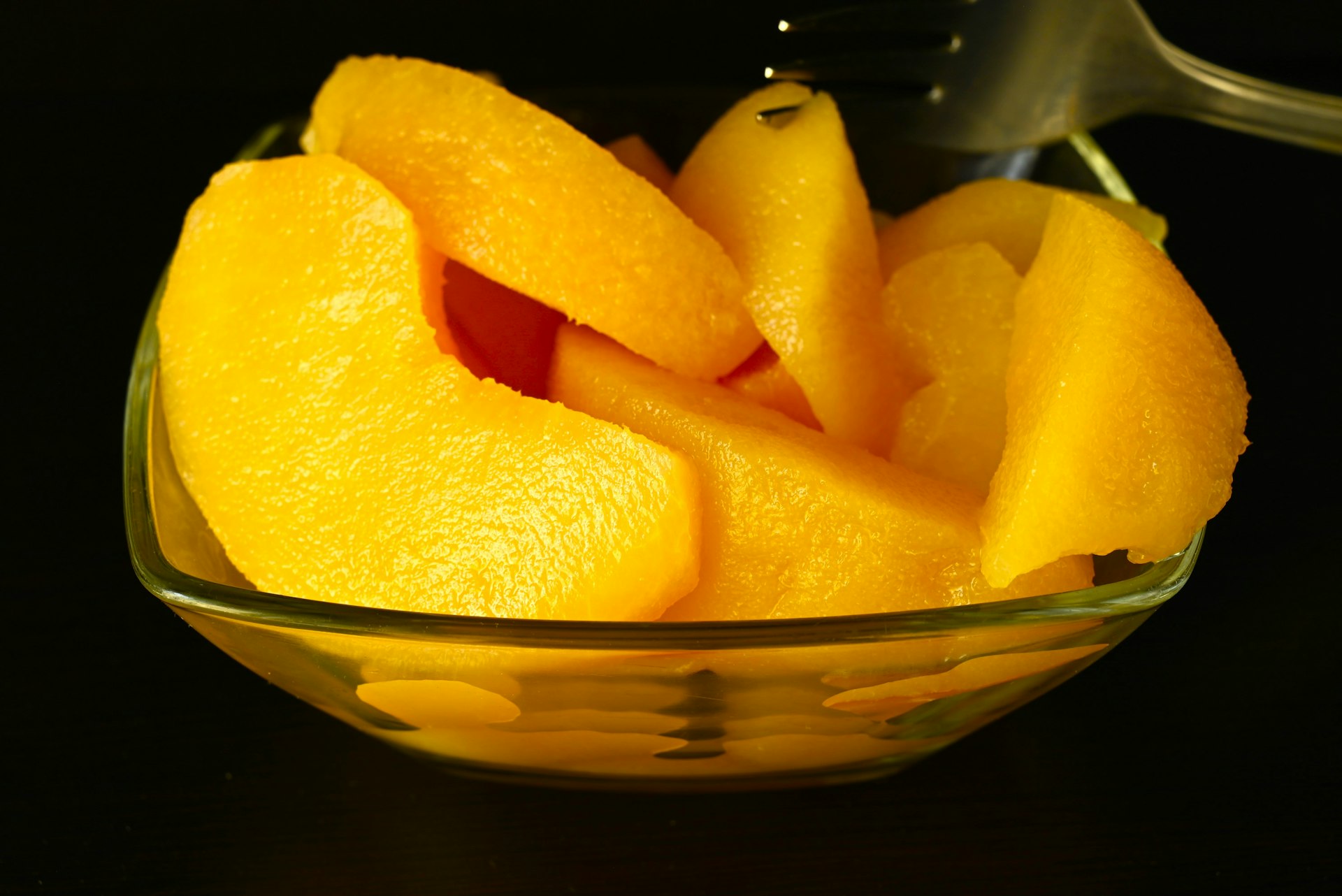 A glass bowl filled with sliced oranges on top of a table